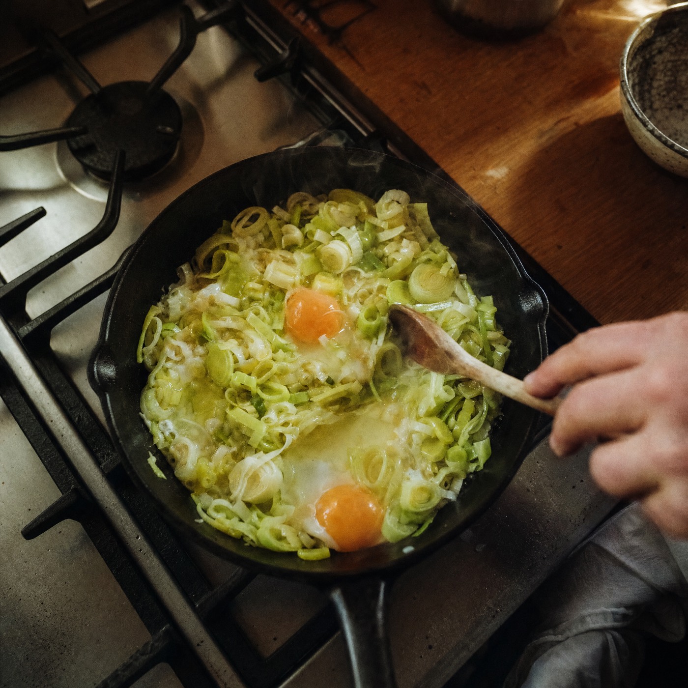 Leeks and eggs cooking in a pan on the hob