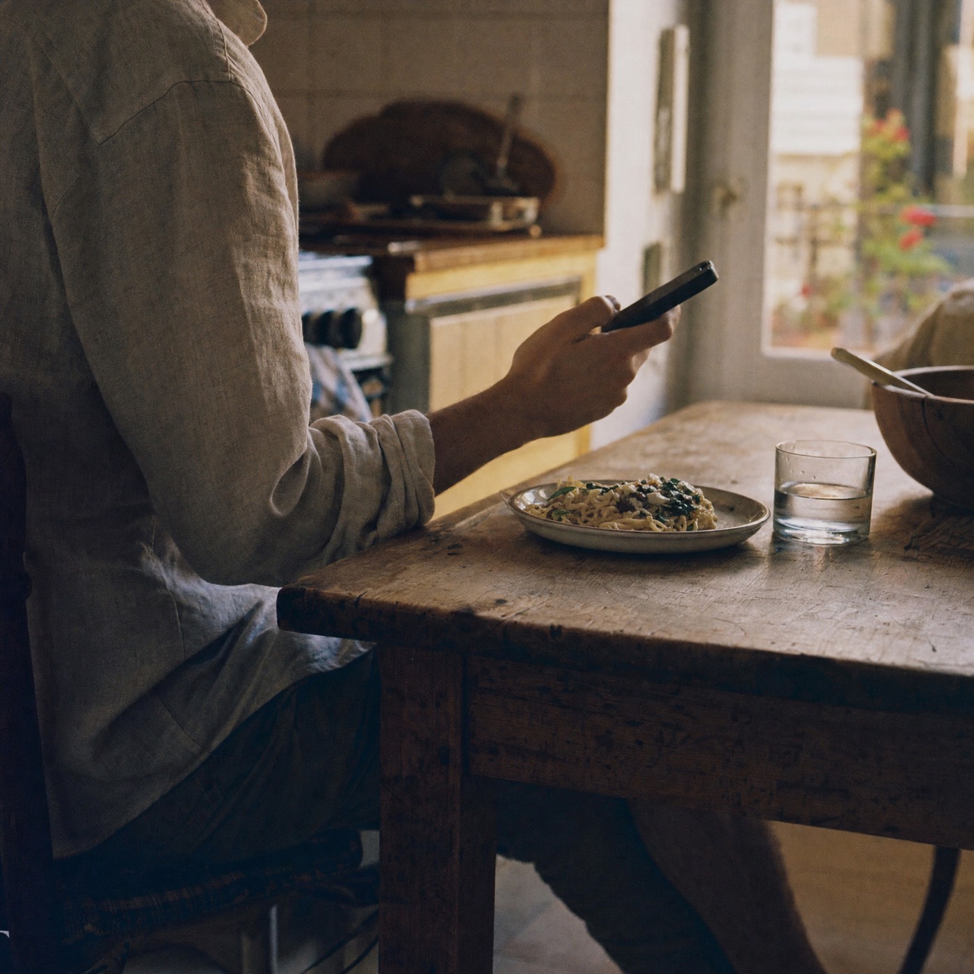 Someone at a kitchen table at the end of the day, phone in hand